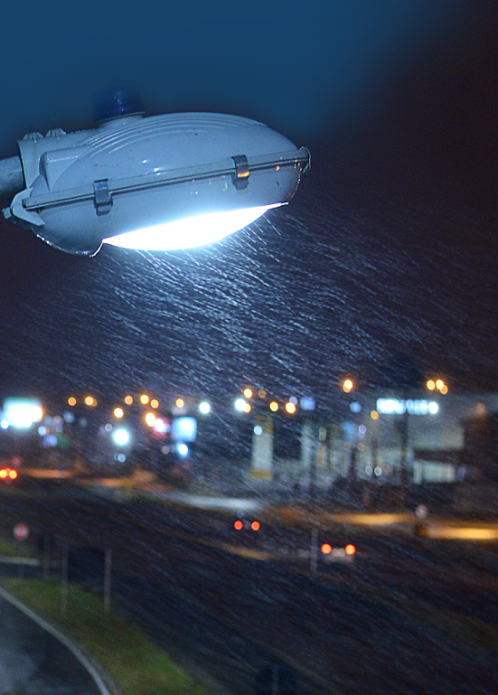 Imagem de um poste iluminando rua num dia chuvoso